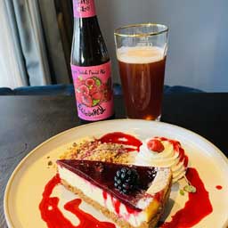 Raspberry beer bottle and glass with cheesecake