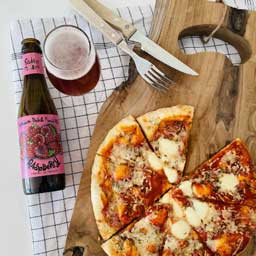 Raspberry beer bottle and glass with pizza