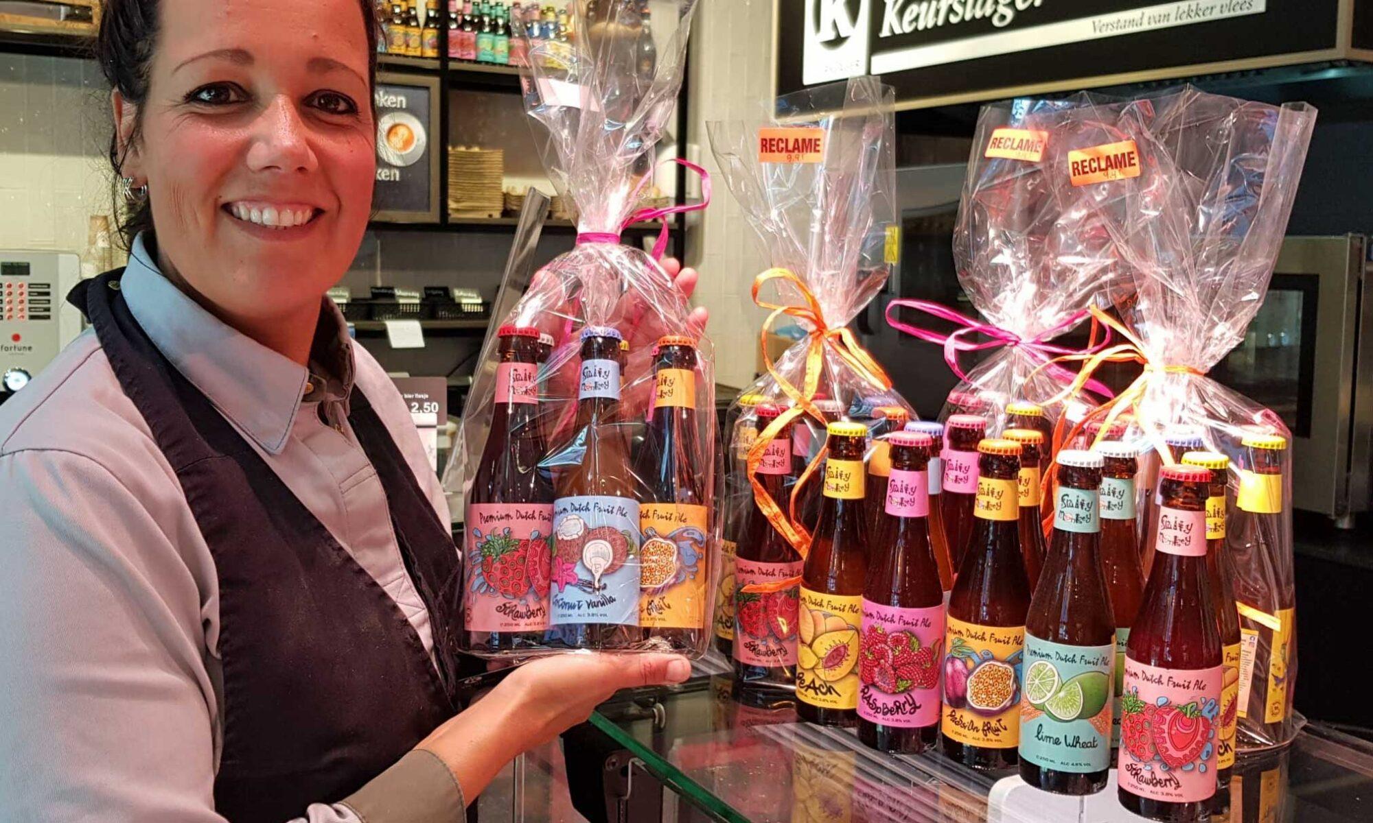 Wrapped set of beer bottles presented by shop assistant in a store where people buy fruit beer