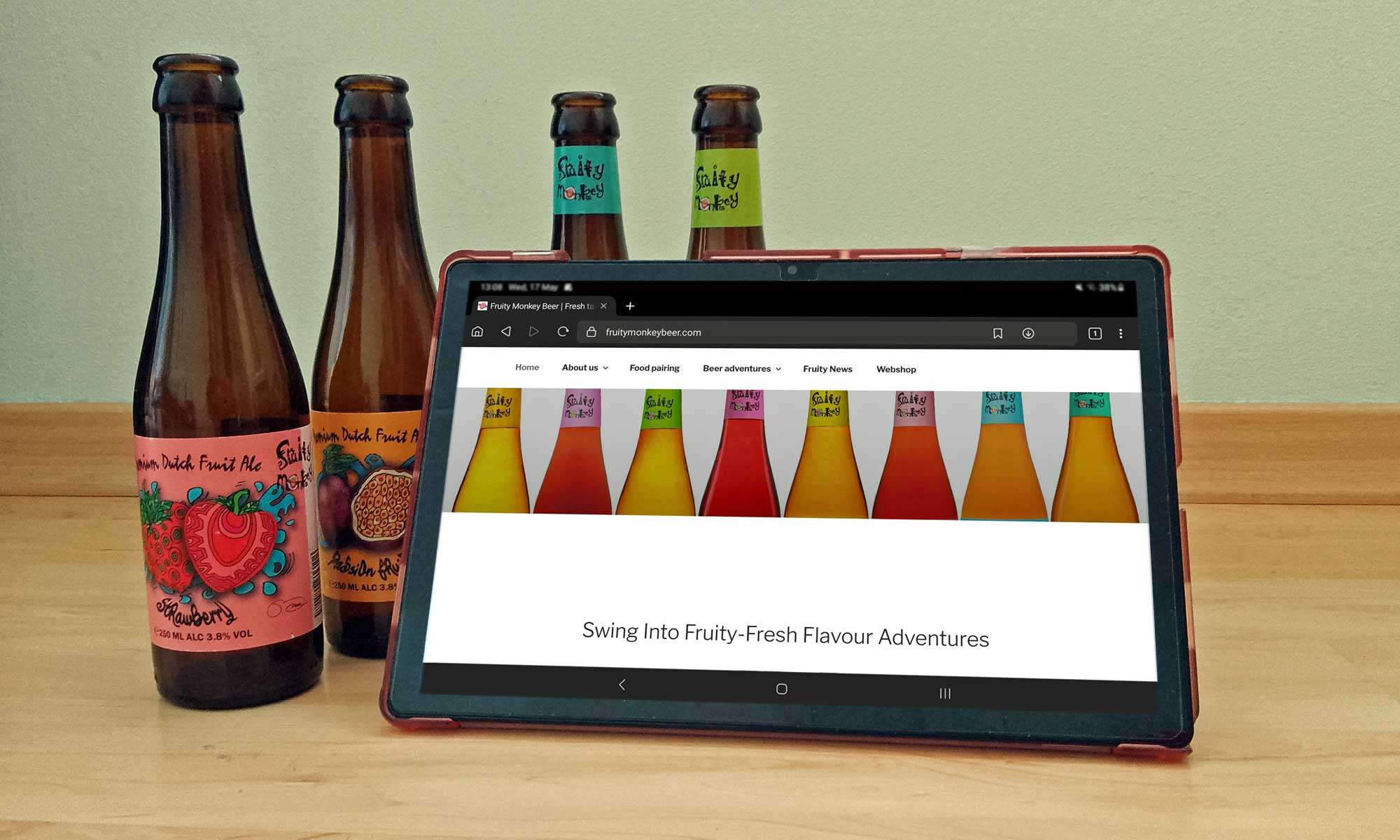 A tablet finding online fruit beer links in front of four empty bottles