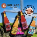 Holland Craft Beer & Fruity Monkey Beer logos in front of blurred windmill with four bottles of fruit beer.