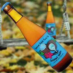 A bottle of Coconut & Vanilla 'Fruity Monkey Beer' in front of a blurred autumn scene.