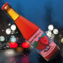 A bottle of Strawberry 'Fruity Monkey Beer' in front of a blurred autumn scene.