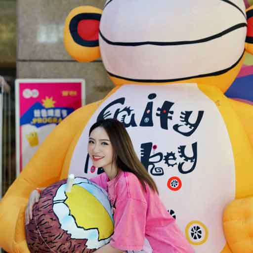 Lady holding a bottle of beer in front of a large yellow inflatable monkey, which is labelled Fruity Monkey and holds a coconut