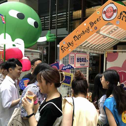 Beer drinkers crowding around a beer stall labelled Fruity Monkey Beer at a festival