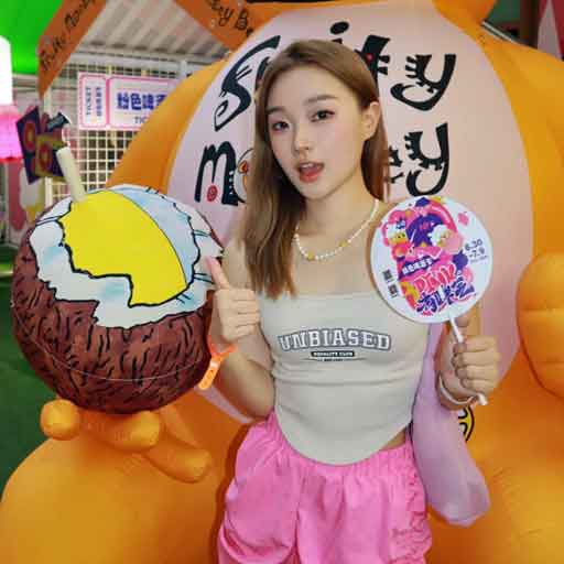 Lady in front of a large yellow inflatable monkey holding a coconut and labelled Fruity Monkey